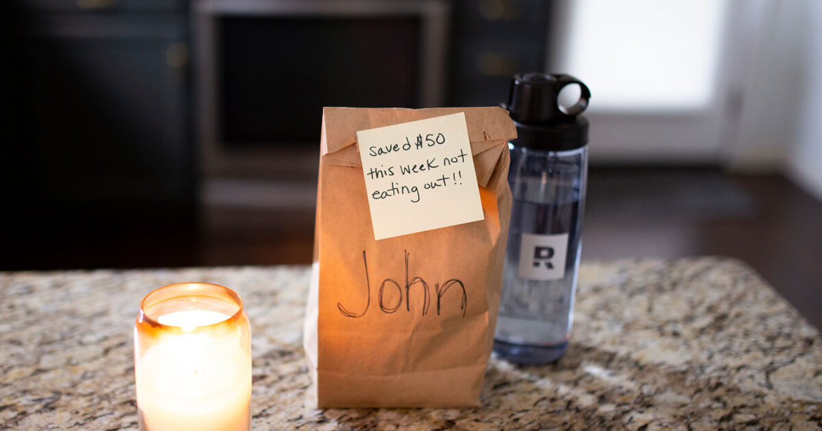 A lunch sack with a sticky-note encouraging a man to save money to pay off his mortgage early. 